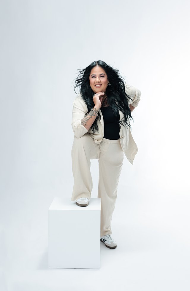 Mujer con traje blanco de pie sobre un cubo blanco.